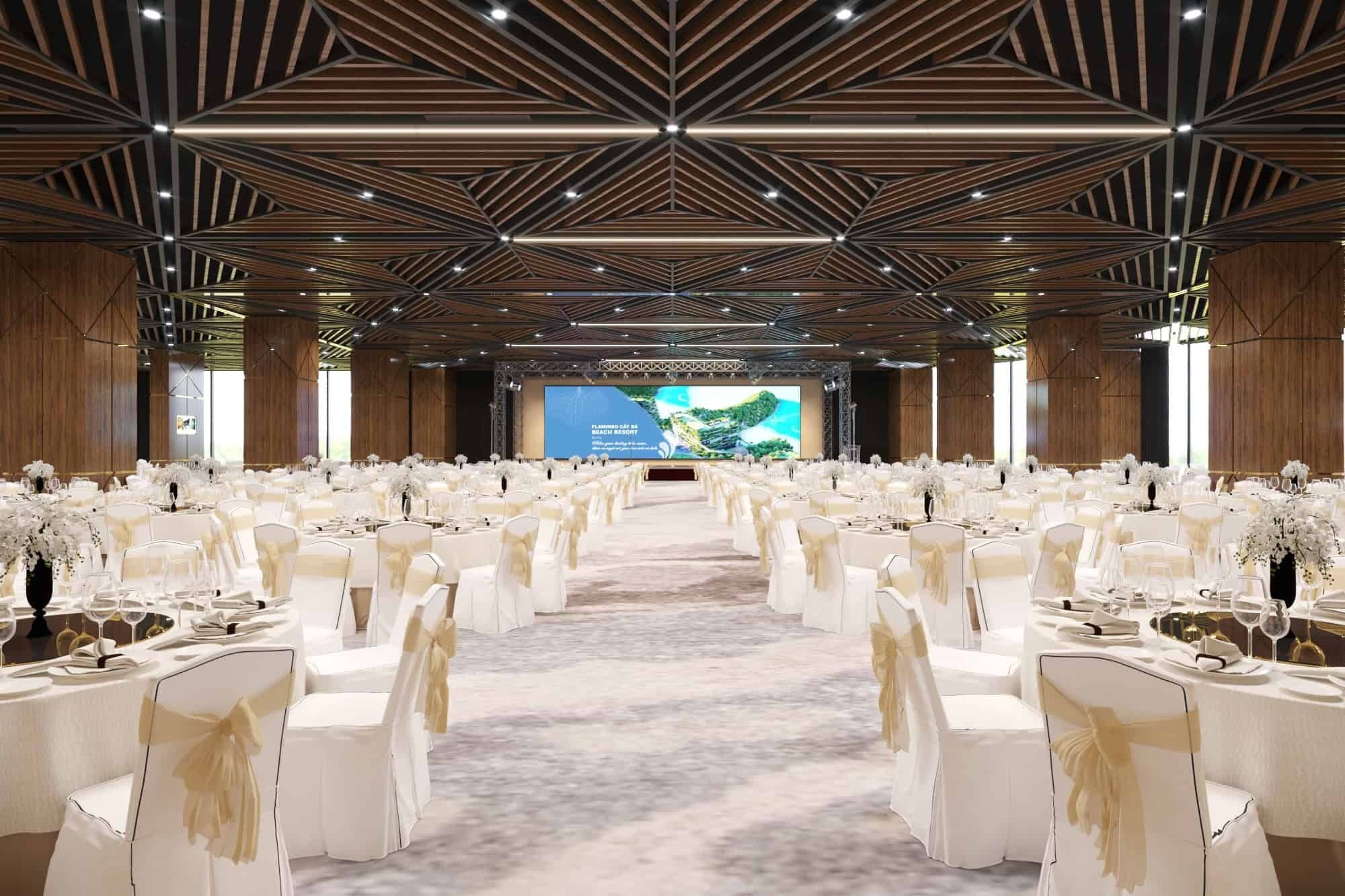 A large conference room with rows of white chairs and tables, a stage with a large screen, and a modern ceiling design.
