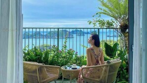 A balcony with wicker chairs, a table, and a view of the sea.