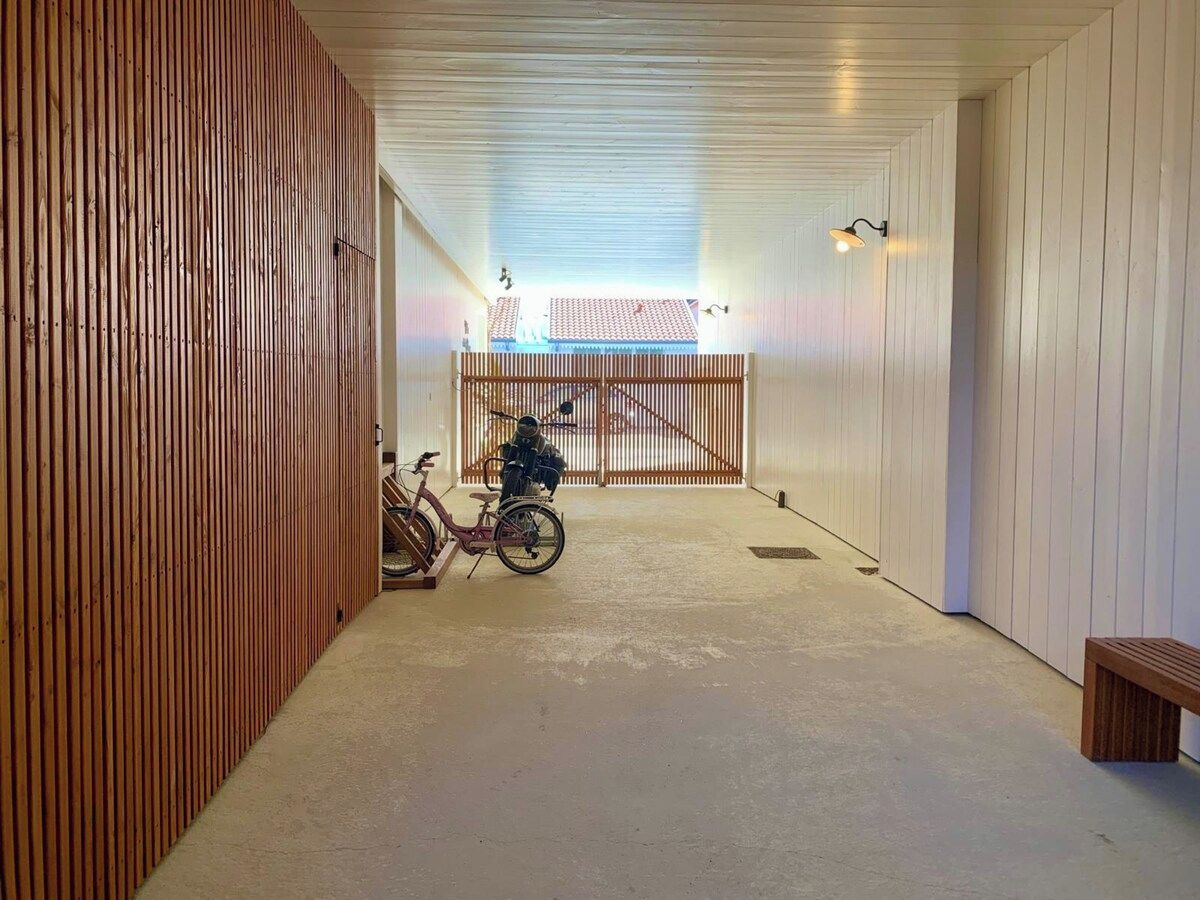 Ein Korridor mit einer Holzwand an der Seite, einer Bank rechts und einem Fahrrad in der Mitte.
