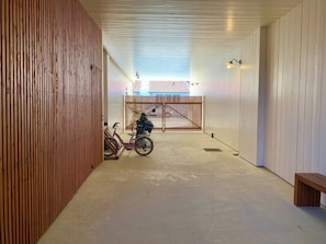 A corridor with a wooden wall on one side, a bench on the right, and a bicycle in the center. - Little idyll in the heart of Cap Ferret A0309 (Lège-Cap-Ferret)