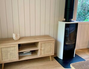 A room with a wooden console table, a black fireplace, and a window with a view of greenery. - Little idyll in the heart of Cap Ferret A0309 (Lège-Cap-Ferret)