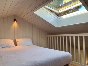 A bedroom with a skylight, a bed with white bedding, and a white railing. - Little idyll in the heart of Cap Ferret A0309 (Lège-Cap-Ferret)