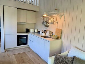 A compact kitchen with white cabinets, a built-in oven, and a countertop with a sink. - Little idyll in the heart of Cap Ferret A0309 (Lège-Cap-Ferret)