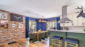 Eine Küche mit Backsteinwand, ein Essbereich mit Tisch und Stühlen sowie ein großes Fenster.