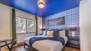 Ein modernes Schlafzimmer mit einem großen Bett, Blick auf Bäume durch das Fenster und einem außergewöhnlichen Wanddesign.