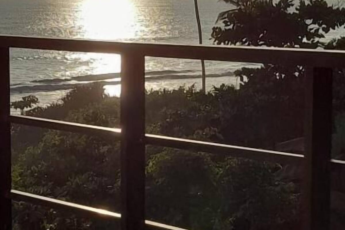 A balcony with a view of the ocean and palm trees.