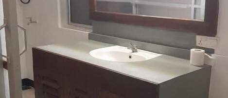 Un baño con un lavabo blanco, un espejo y un inodoro.