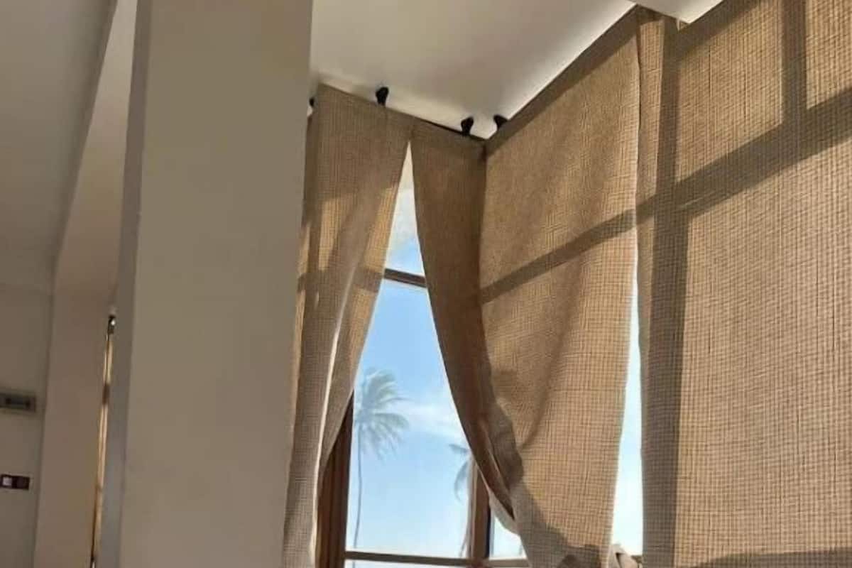 A bedroom with a bed, a window with curtains, and a view of the outdoors.