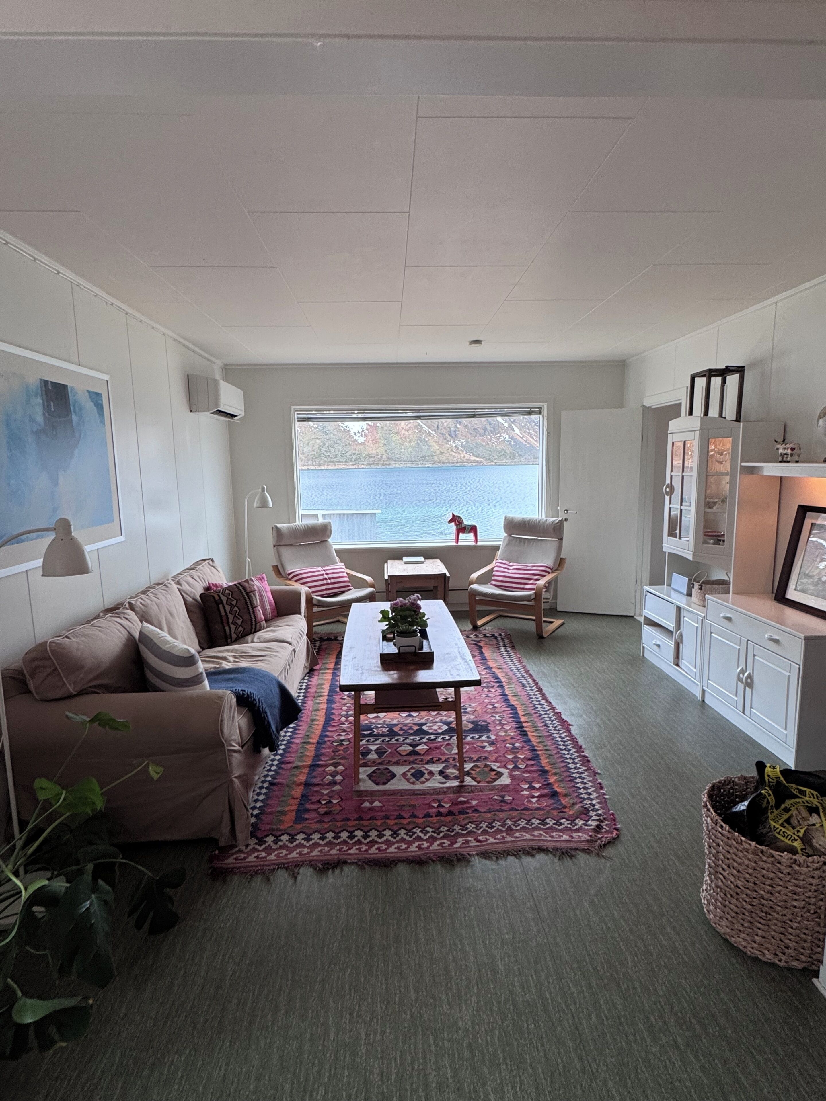 Ein gemütliches Wohnzimmer mit einer Couch, Sesseln, einem Couchtisch und Blick auf das Meer.