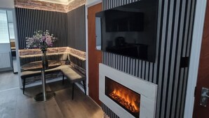 Ett modernt vardagsrum med en öppen spis, en sittgrupp och en tv som är monterad på väggen.