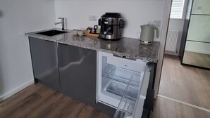 Ett modernt kök med ett inbyggt kylskåp, en kaffebryggare och en diskho.