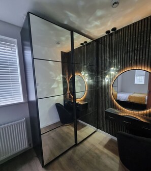A modern bedroom with a large mirror, a vanity with lights, a bed, and a radiator. - Apartment Sleeps 4 With Enclosed Garden (St Albans)