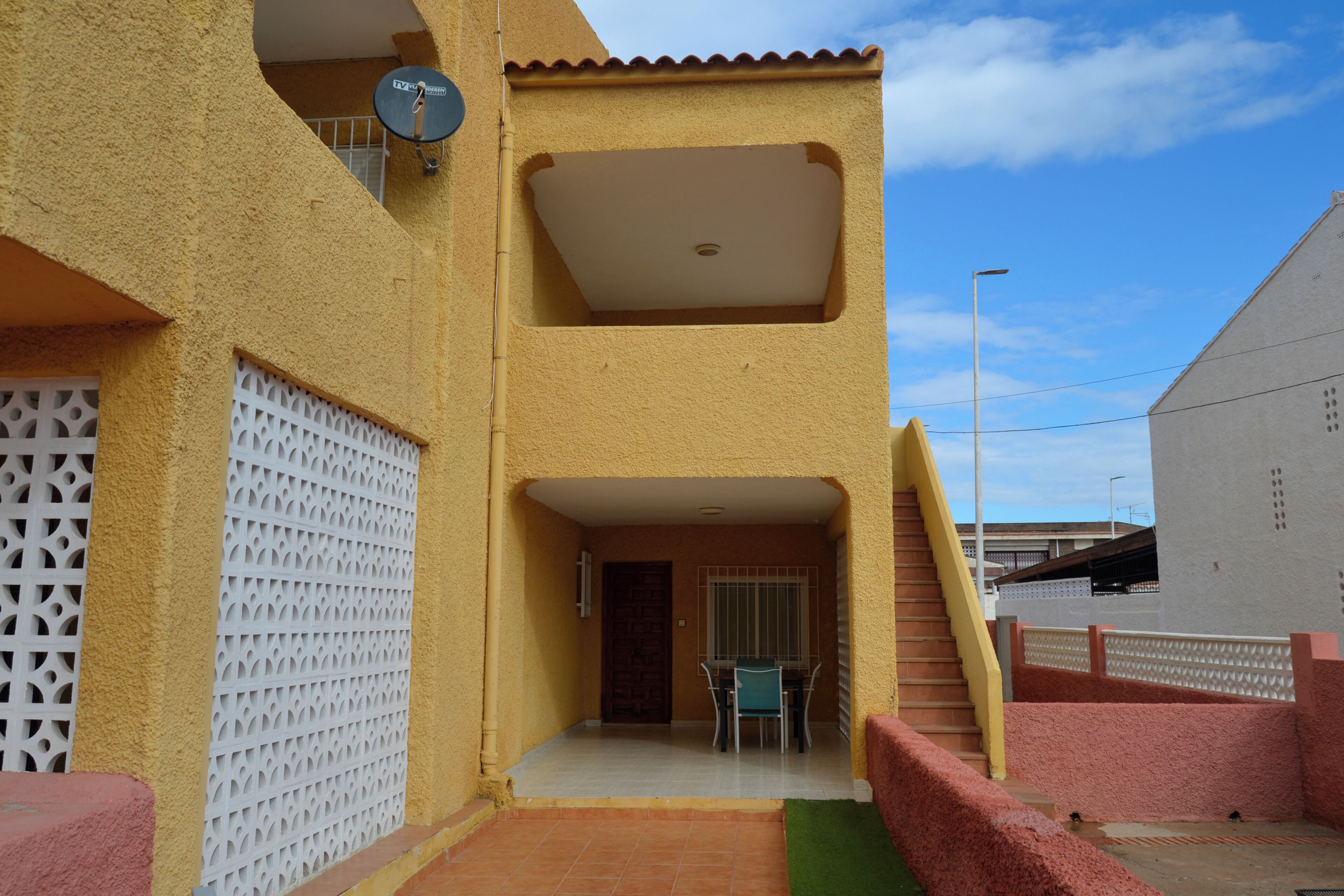 Un edificio con un porche cubierto, una puerta y una escalera.