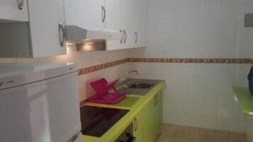 A kitchen with white cabinets, a green countertop, and a pink dish rack.