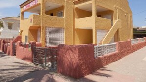 Un immeuble doté d’un toit plat, de plusieurs balcons et d’une entrée sécurisée par un portail.