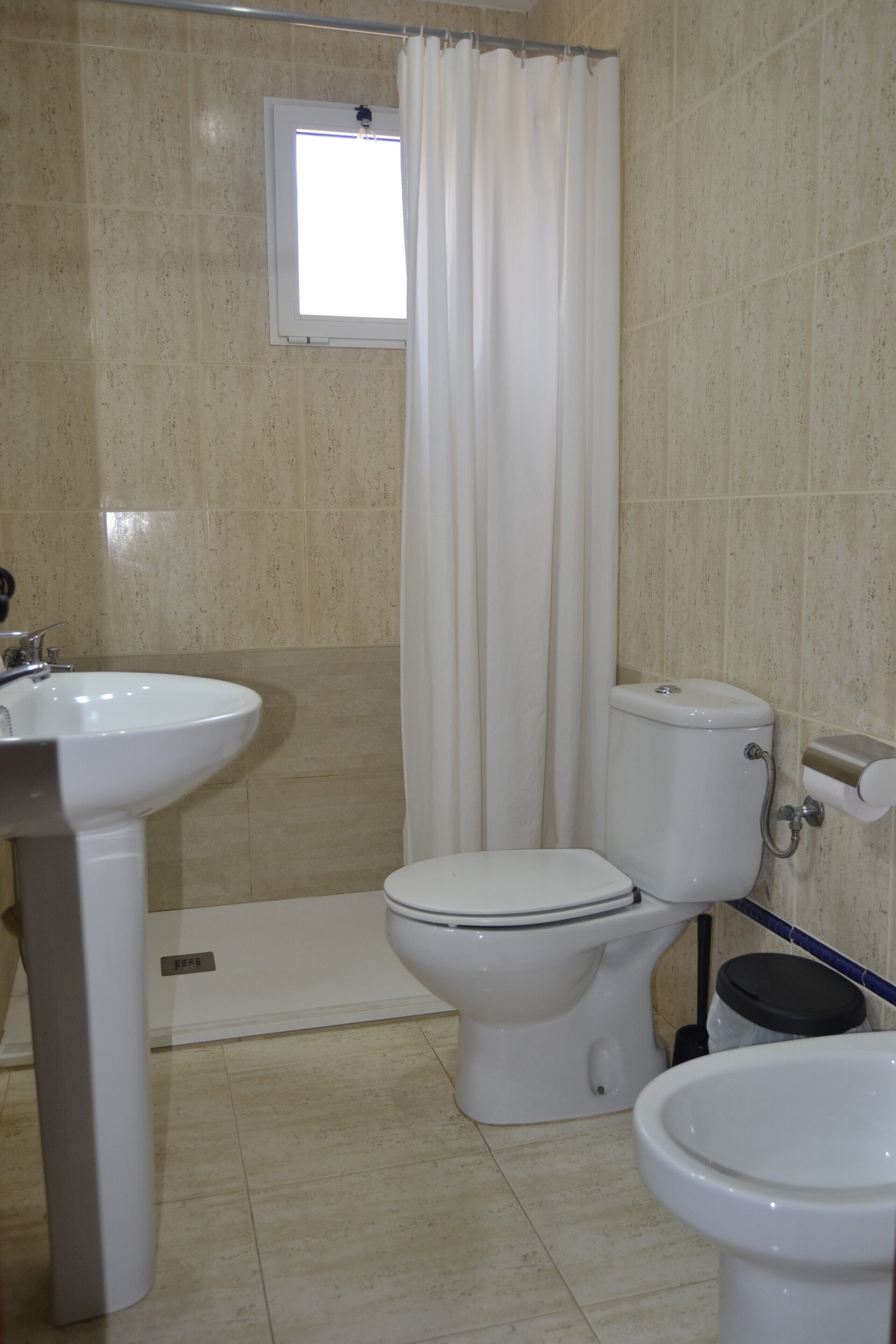 Un baño con inodoro, lavamanos y bidé.