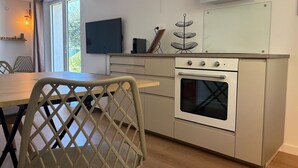 Eine moderne Küche mit Einbauofen, einem Esstisch mit Stühlen und einem großen Fenster.