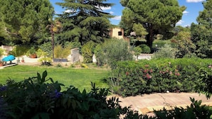 A garden with various trees, a stone wall, and a building partially obscured by foliage. - Bastide provençale - Private pool 11m - Air conditioning - Pizza oven - Aix 5min (Aix-en-Provence)
