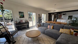 A spacious living room with a grey sofa, a wooden coffee table, and a piano. - Bastide provençale - Private pool 11m - Air conditioning - Pizza oven - Aix 5min (Aix-en-Provence)