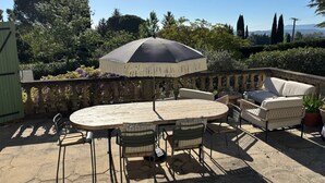 An outdoor patio with a round table, chairs, a sofa, and an umbrella. - Bastide provençale - Private pool 11m - Air conditioning - Pizza oven - Aix 5min (Aix-en-Provence)