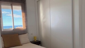Ein Schlafzimmer mit Bett, Nachttisch, Lampe, Deckenventilator und einer Schiebetür.