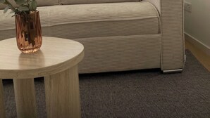 Ein Wohnzimmer mit einer Couch, einem runden Holztisch und einem Blumentopf.