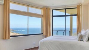 Ein Schlafzimmer mit einem großen Bett, Meerblick und einem Balkon.