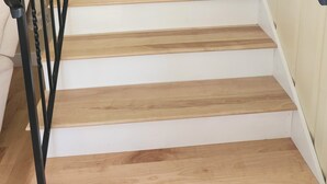 Una escalera con escalones de madera y barandillas negras, que conduce a una plataforma.