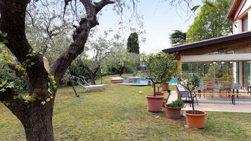 Ein Garten mit Swimmingpool, Terrassenmöbeln und Blumentöpfen.