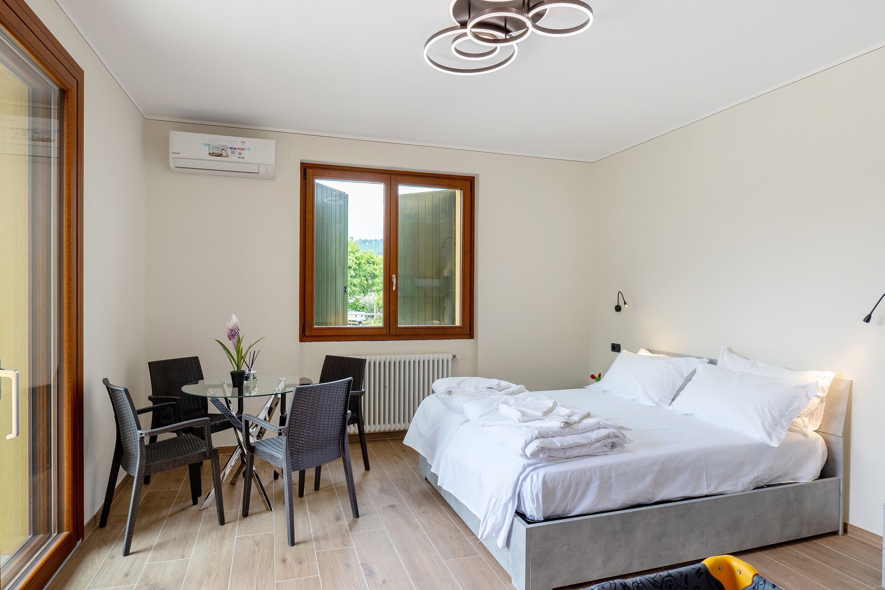 Une chambre à coucher comprenant un lit, une table avec des chaises, une fenêtre et un appareil de climatisation.