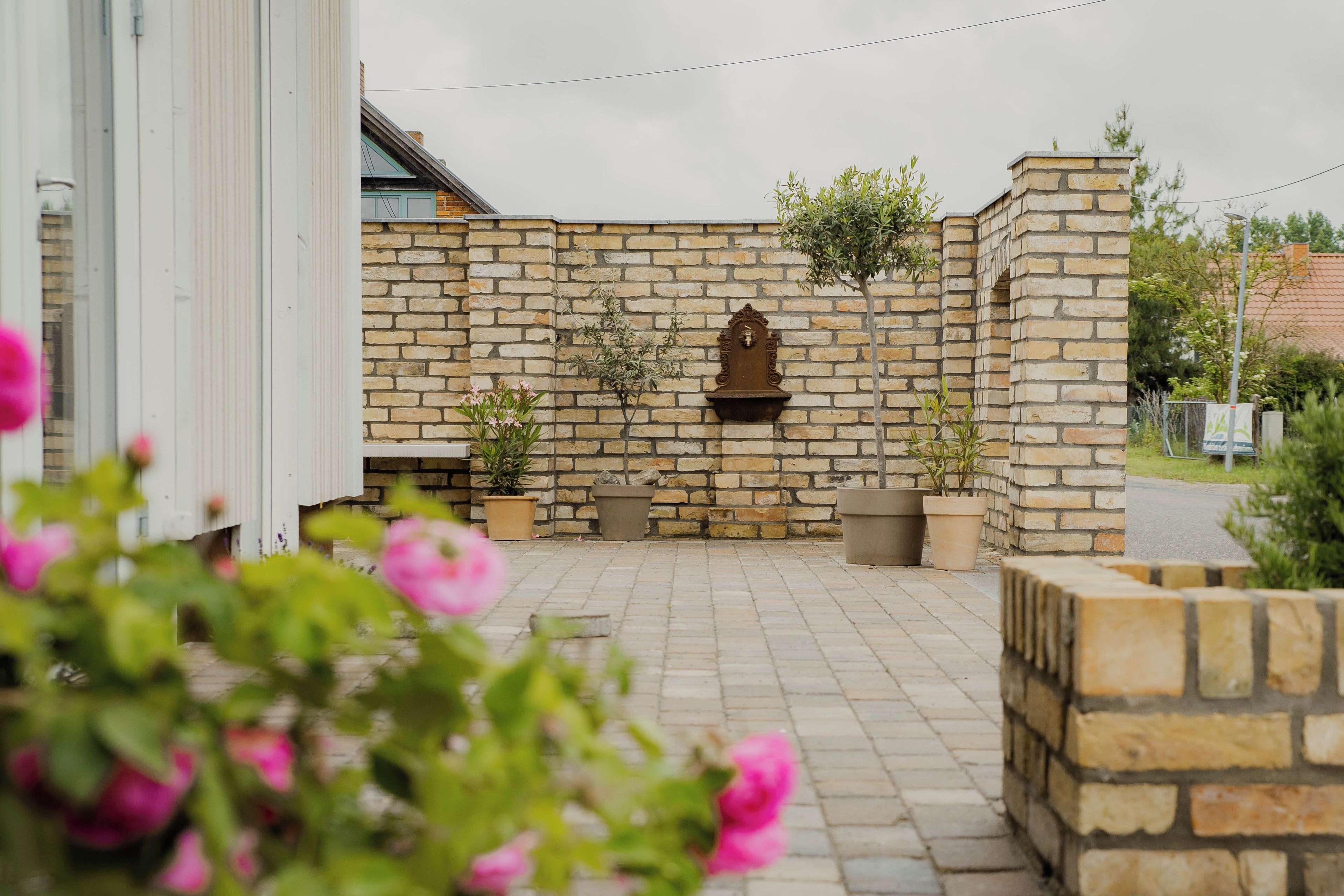A stone wall with a water feature and potted plants.
