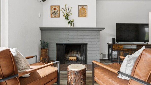 A living room with a fireplace, leather sofas, a coffee table, and a flat-screen TV.