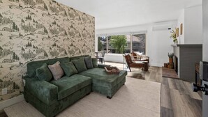 A living room with a green sofa, a fireplace, and a large window.