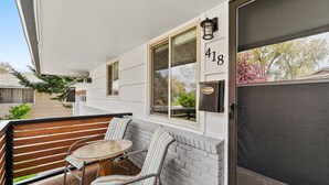 A balcony with a wooden bench, a striped chair, and a small table.