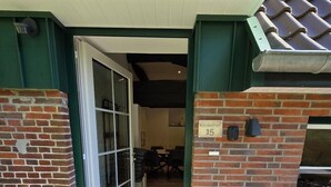 Fachada de edificio de ladrillo, una puerta de acceso y un cartel con número.