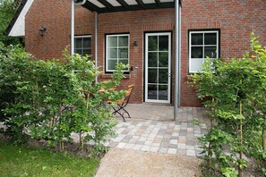 A brick building with a covered patio area, a door, and a window. - Spacious 3-room apartment for up to 4 people in Bad Zwischenahn. The approx. 60 m², stylishly furnished 3-room apartment for up to 4 people is located on the Klosterhof Aue, right in the heart of Bad Zwischenahn. (Bad Zwischenahn)