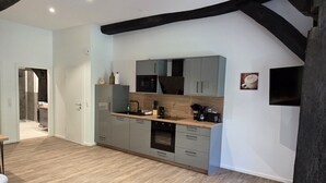 Een moderne keuken met grijze kastjes, een houten aanrechtblad en een inbouwoven.