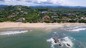 A coastal town with a beach, buildings, and greenery. - Iguana Surf Boutique Hotel Tamarindo (Tamarindo)