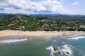 Un pueblo costero con playa, edificios y zonas verdes.