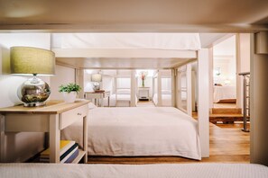 A bedroom with a bed, bedside table, lamp, and a view of another room. - Iguana Surf Boutique Hotel Tamarindo (Tamarindo)