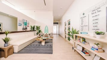 A modern hotel lobby with a sofa, coffee table, and a wall displaying daily conditions and activities.
