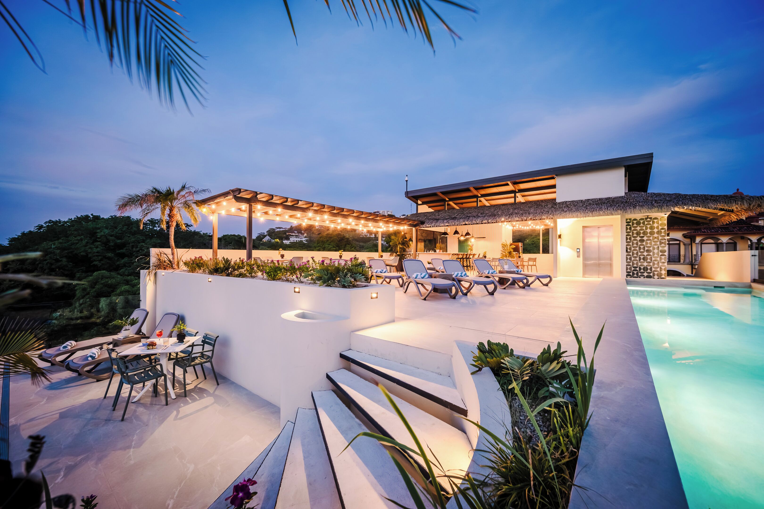 A modern outdoor pool area with lounge chairs and a pergola, surrounded by a landscaped garden.
