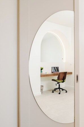 Una habitación con un espejo curvo que refleja un escritorio, una silla y un ordenador portátil.