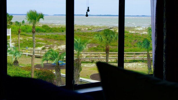 A view through a window with a beach and palm trees in the background. - Harbor Hideaway …just steps to the beach and pool! (Harbor Island)