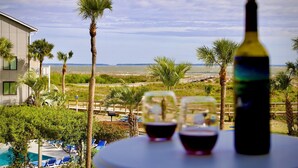 A table with a bottle and glasses, overlooking a pool and palm trees with a view of the ocean. - Harbor Hideaway …just steps to the beach and pool! (Harbor Island)