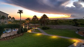 A residential area with a well-maintained lawn, a pathway, and a view of the ocean at sunset. - Harbor Hideaway …just steps to the beach and pool! (Harbor Island)