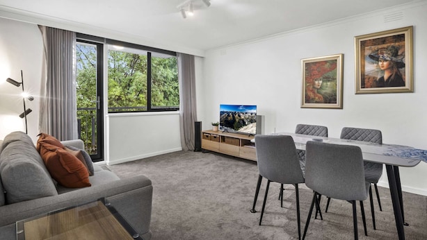 A modern living room with a sofa, TV, dining table, chairs, and artwork on the wall. - Comfortable Stay Near Melbourne's West End (Melbourne)