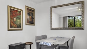 A dining area with a table, chairs, a fireplace, and two framed paintings on the wall. - Comfortable Stay Near Melbourne's West End (Melbourne)