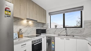 A modern kitchen with white cabinets, a built-in oven, a dishwasher, and a microwave. - Comfortable Stay Near Melbourne's West End (Melbourne)