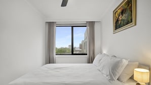 A hotel room with a bed, a nightstand, a lamp, a window with curtains, and a painting on the wall. - Comfortable Stay Near Melbourne's West End (Melbourne)